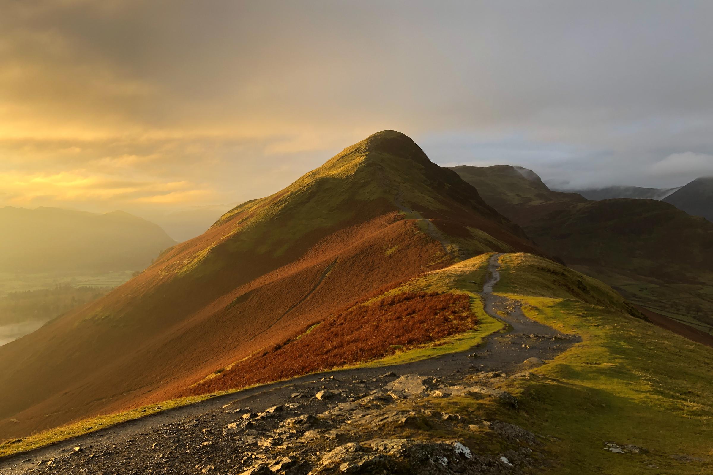 After an early walk up to the summit with no chance of a sunrise, I decided to head back for breakfast.  I suddenly felt the warmth of the sun on my neck as the sun broke through a gap in the clouds and spun around and fumbled with my phone to capture the view before me.  Golden side light illuminated Cat Bells, accentuating the contours of her flanks in full autumnal plumage.  By the time I got the big cam out the light was gone.