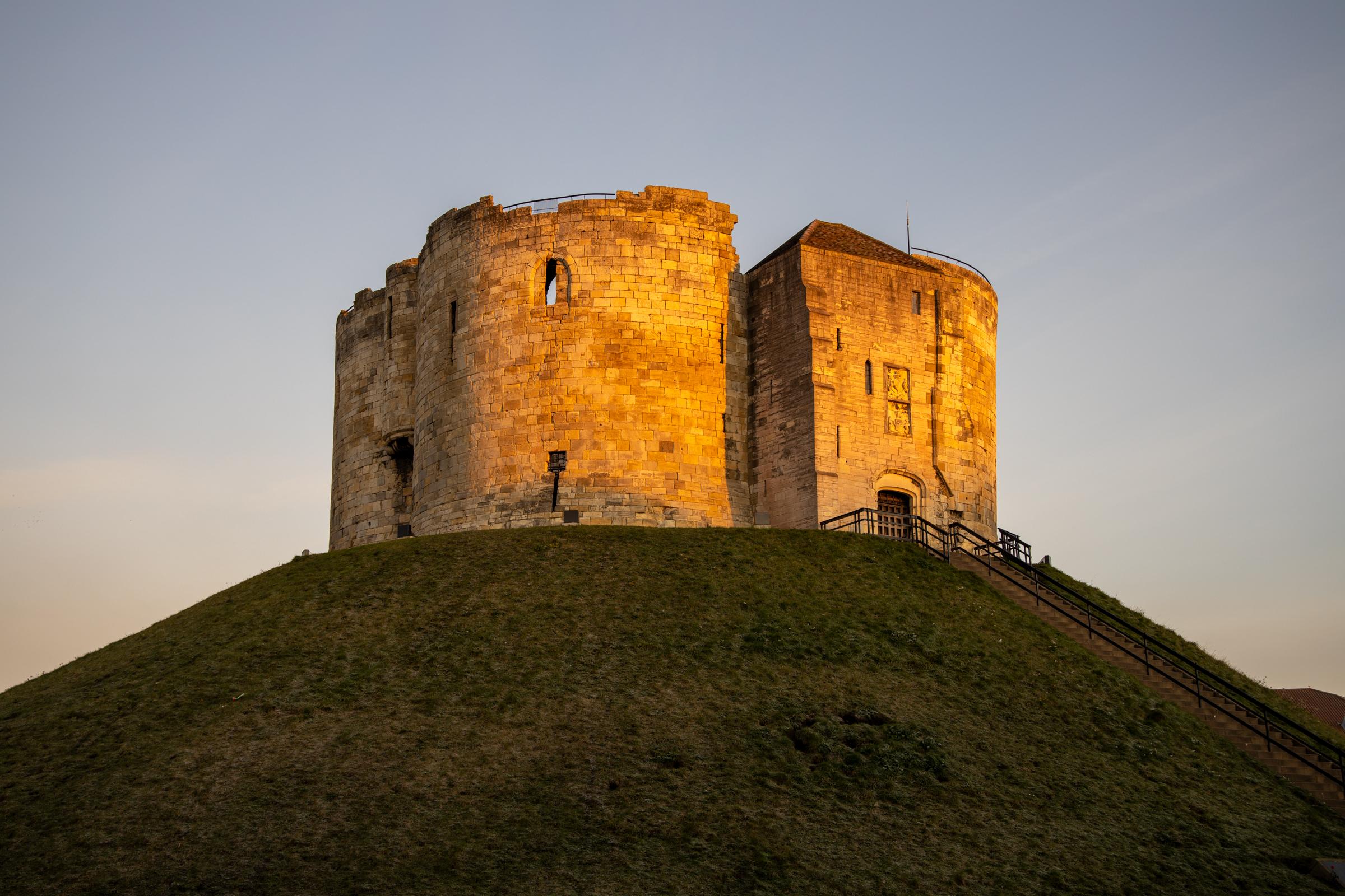Cliffords Tower sidelit by the golden glow of a winters sunrise