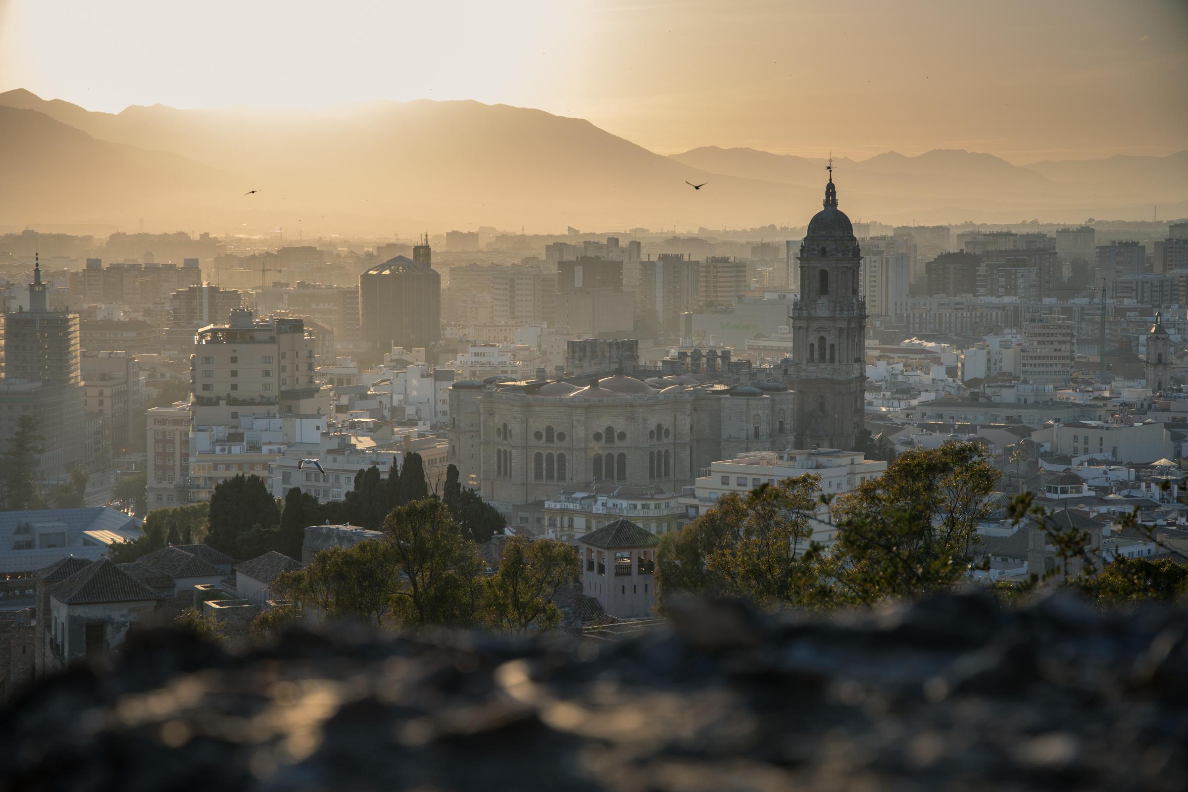 Overloking Alcazaba towards Malaga Cathedral and the rest of the city as the sun sets over the distant mountains