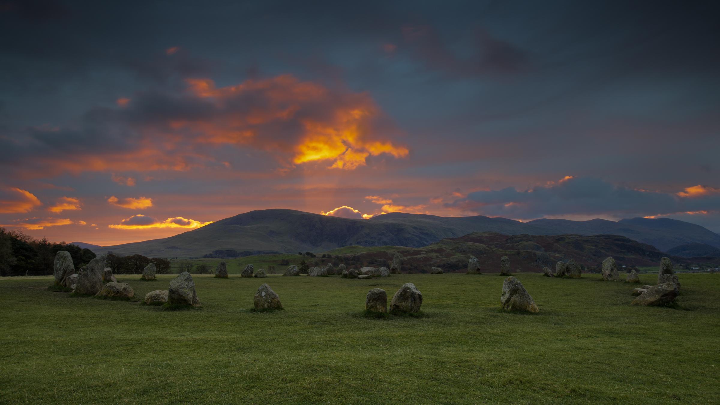 Autumnal early morning light catches the clouds over the Helvellyn range at Castlerigg Stone Circle in the Lake District.  The central cloud has the look of a phoenix alight in the fire colours of the morning sky.